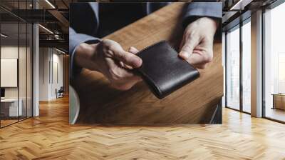 A business man at a wooden table holds a leather wallet in a cafe and waits for a lunch bill. No face, close-up Wall mural