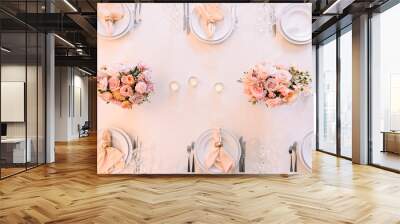 Banquet, restaurant. Table setting. White plates with a gold rim, golden cutlery, glasses. Peach-colored napkin with a golden ring. Peach pink floral arrangements Wall mural