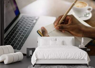 unrecognizable, cropped multiracial dark skin man using laptop, taking notes in workbook, drinking c Wall mural