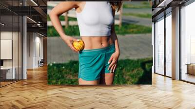 young athletic girl does massage with spiky rubber ball stomach to tighten skin and beautiful abs muscles on sunny day in park. Wall mural