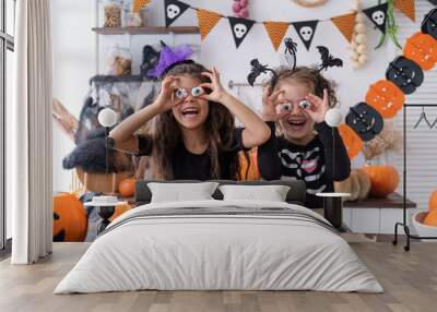 two diverse kids girl in costume of witch, having fun at home in kitchen, celebrating Halloween Wall mural