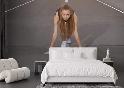 Young athlete on the treadmill in a low start position Wall mural