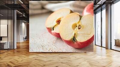 Two apples are sliced in half on a table, showcasing their freshness and vivid colors Wall mural