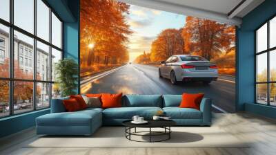 White car driving fast on a road with colorful autumn trees at sunset Wall mural