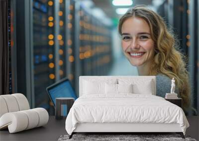 Young, smiling it engineer is working on a laptop in a data center Wall mural