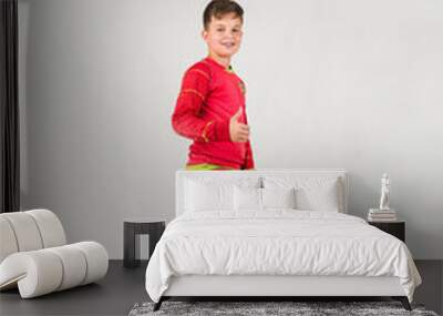 a happy young football player in a red uniform plays with a soccer ball on a white background with a place for text Wall mural