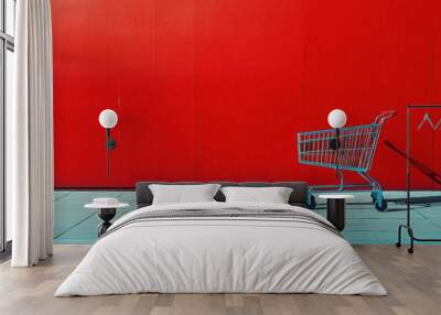 A lone shopping cart rests beside a vibrant red wall in an urban area during the afternoon hours Wall mural