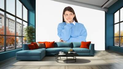 Cute woman standing in blue sweatshirt, holding palm on cheek and leaning face on it, being bored and tired of uninteresting talks, feeling indifferent to what happening over white wall Wall mural