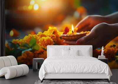 A serene moment featuring hands holding a lit oil lamp surrounded by vibrant marigold flowers, symbolizing light and celebration. Wall mural