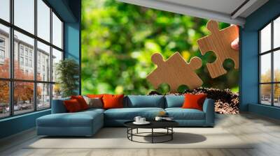 Earth and environment conservation concept, man holds jigsaw puzzle in hand on green environmental background. ,Environmental conservation, Net Zero and Carbon Neutral Concepts. Wall mural