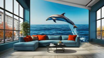 A dolphin performing acrobatic flips in the air, against a backdrop of deep blue sea and clear skies, showing off its natural agility and playful spirit. Wall mural