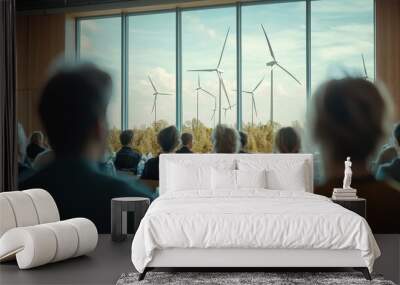 A group of people are sitting in a room looking out a window at a wind farm Wall mural