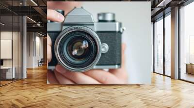 A person is holding a camera with a black lens Wall mural