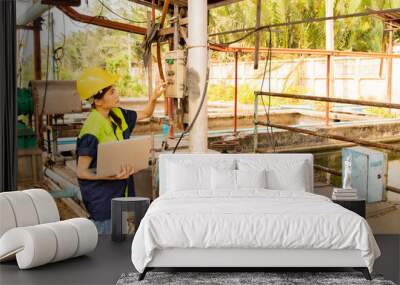 Female technician worker holding laptop inspects control system air pump sanitation station wastewater treatment industrial factory pond sludge separation wastewater drainage preserve the ecosystem. Wall mural