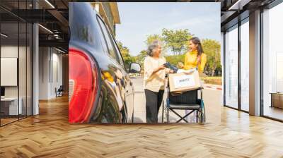 Happy elderly mother and her Asian philanthropist daughter drive to the shelter to donate wheelchairs and necessary charity clothes in cardboard boxes to the disabled and victims in need. Wall mural