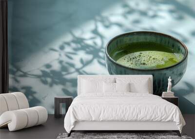 A cup of matcha green tea and matcha powder with a matcha green tea maker on a simple background. Wall mural