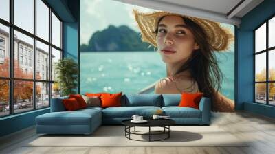 A woman wearing a straw hat travels on a boat outside a beautiful island resort. Wall mural