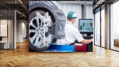 Auto mechanic installs sensors during suspension adjustment. Wheel alignment work at a car repair station Wall mural