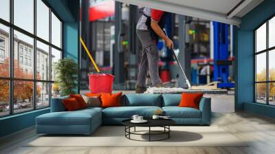 Car mechanic cleaning the garage floor at the auto industry shop workshop Use a mop to clean water from the epoxy floor in the car repair center. Wall mural