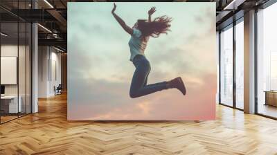 Woman jumping against sunset sky with joy Wall mural