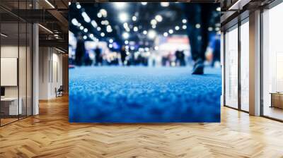 Blurred background of business fair or exhibition hall with lights and people on a blue carpet floor at event venue, captured using a Nikon D850 with 24-70mm f/2.8 lens. Wall mural