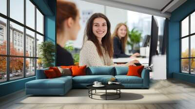 Female Creative Professional Smiling While Working on a Computer with a Co-Worker in an Office, Photo-Realistic High-Resolution Image with Soft Shadows and Clean Focus. Wall mural