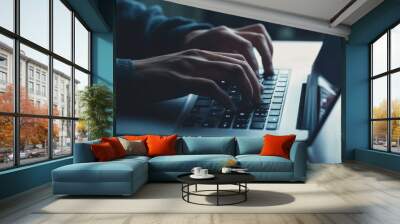 Focused individual typing on a laptop, representing detailed work in business technology or online writing, with one hand on the keyboard and the other hovering above it. Wall mural