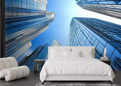 Ground-up perspective of modern skyscrapers with glass facades against a blue sky, showcasing a futuristic urban landscape with realistic shadows, reflections, and high-definition detail. Wall mural