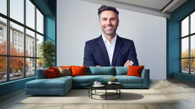 Smiling man in a navy suit with arms crossed against a light grey background, professional studio portrait with soft lighting and sharp focus. Wall mural