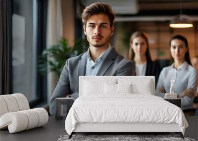 Confident young businessman exuding leadership in modern office setting, arms crossed, overseeing team dynamics with a strong presence and visionary outlook Wall mural