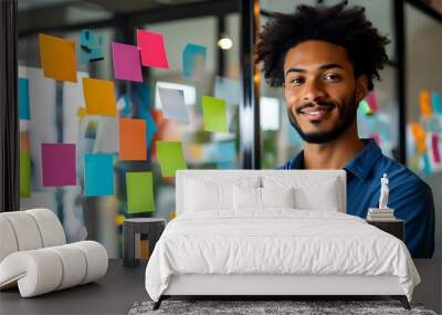 Confident young businessman in blue casual attire leading a dynamic creative meeting with colorful sticky notes and a clear mind map on a glass board Wall mural