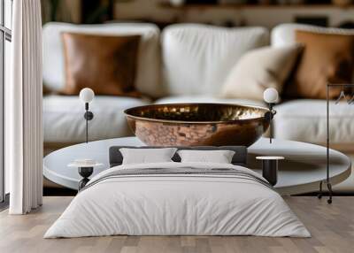 Elegant copper bowl on a pristine white table, paired with a stylish white couch adorned with brown and white decorative pillows Wall mural