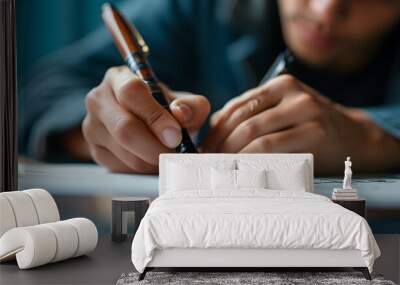 Focused writing on paper with a pen, capturing concentration against a calming blue background Wall mural