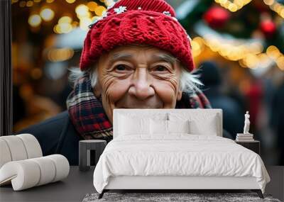 Joyful elderly man celebrating holiday spirit at Christmas market with red knit hat and plaid scarf surrounded by vibrant festive decorations Wall mural