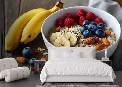 Nutritious oatmeal porridge topped with bananas, blueberries, raspberries, and almonds in a white bowl on a rustic wooden table Wall mural