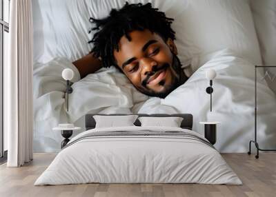 Peaceful slumber of a young Black man in white attire resting on a pristine white bed, embodying tranquility and comfort. Wall mural