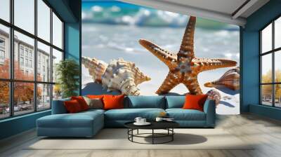 Starfish and conch shells on pristine white beach sand with vibrant blue sea water in the background Wall mural