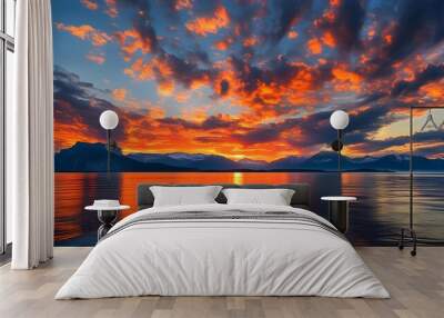 Vibrant sunset sky over tranquil sea with majestic mountains and enchanting clouds in shades of orange and red Wall mural