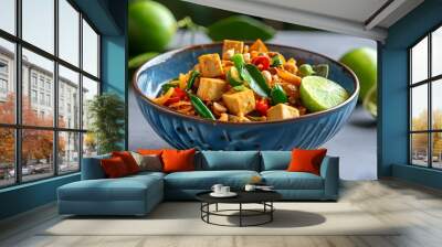 Vibrant vegetarian pad Thai with tofu, peanuts, and fresh lime served in a blue ceramic bowl on a stylish gray table Wall mural