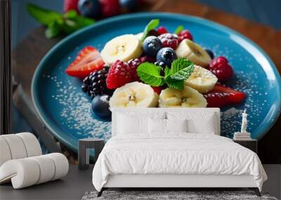 Colorful berry medley dessert topped with banana slices, fresh mint, and a dusting of powdered sugar on a vibrant blue plate Wall mural