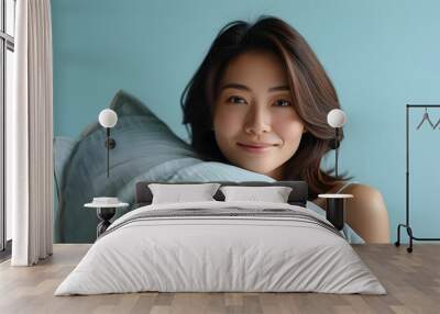 Serene moment of a woman embracing a pillow against a soft blue backdrop, illuminated by gentle lighting, radiating peace and contentment Wall mural