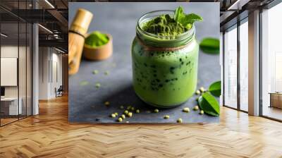 Vibrant green matcha smoothie with coconut flakes and powder in a glass jar, displayed on a textured gray background Wall mural