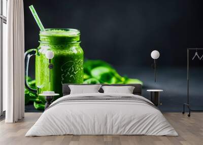 Vibrant green smoothie in a mason jar with a straw, framed by fresh spinach leaves on a dark backdrop Wall mural