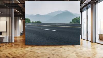 Tranquil Road Leading to Serene Mountains Under Misty Sky Wall mural