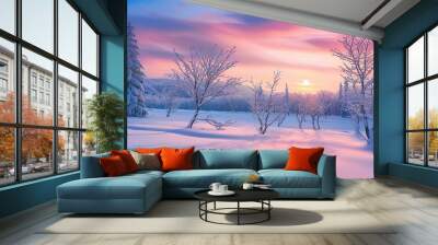 A beautiful winter landscape with trees covered in snow, and the sky painted by colorful pastel hues of sunrise. The sun rises over distant hills, casting long shadows on the snowy ground below. Wall mural