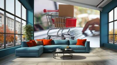 Digital online shopping concept, miniature cart with boxes on laptop keyboard and blurred web store interface background Wall mural