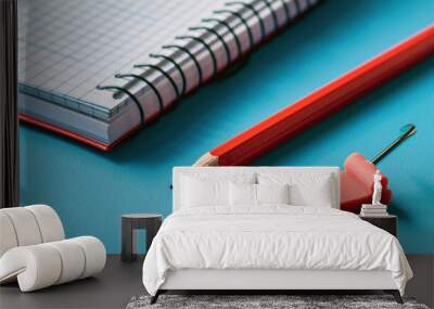 Photo of A red pencil and notebook on blue background Wall mural