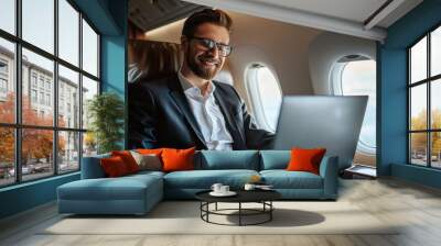 Portrait of handsome businessman working on laptop while flying on airplane Wall mural