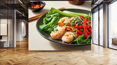 A plate of salad containing red peppers, seafood and green vegetables, served with fragrant rice noodles sprinkled with white sesame seeds, chopsticks placed next to it, and a light background. Wall mural