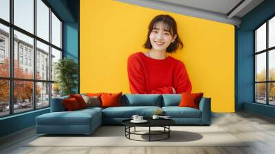 Full length portrait of a smiling japan woman in an red sweater and jeans standing isolated on a yellow background Wall mural